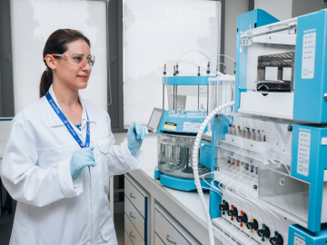 Female scientist in a laboratory operating advanced equipment for Dissolution testing, highlighting expertise and precision in researching. 