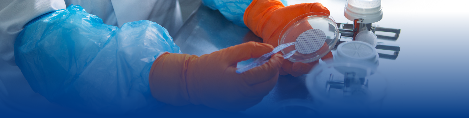 Close-up of a researcher’s hands wearing safety goggles and a lab coat, handling a sample in a Petri dish in a sterile laboratory environment. Showcasing precision and expertise in BioPharma Product Testing.  