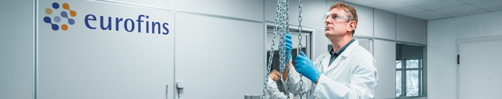 Close up of a scientist wearing a white lab coat, protective goggles, and blue gloves conducting Container Closure Integrity Testing in a Eurofins laboratory. Showcasing advanced equipment and expertise in BioPharma Product Testing within a high-precision research environment.